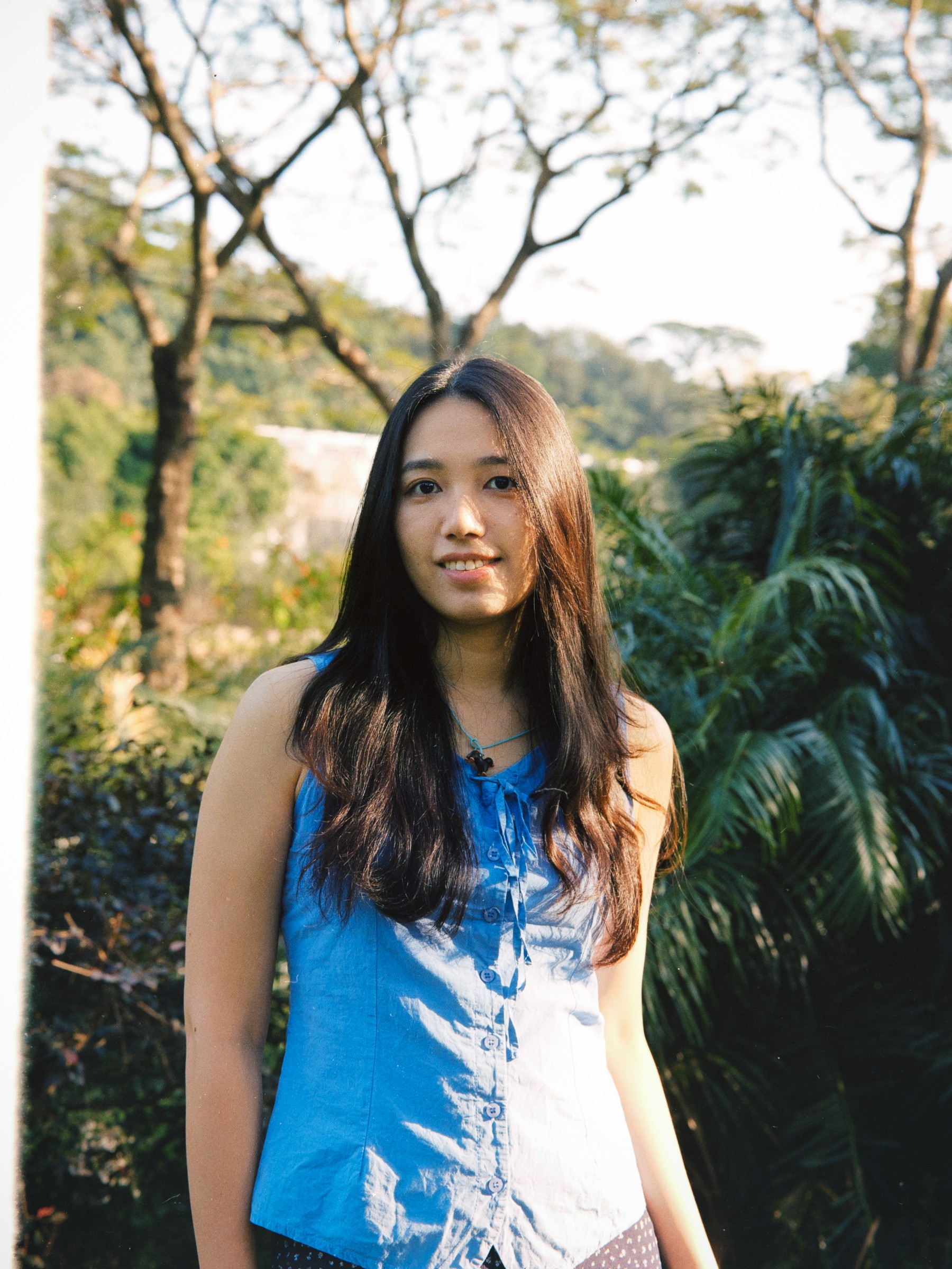 Portrait of a woman in blue among sunlit trees