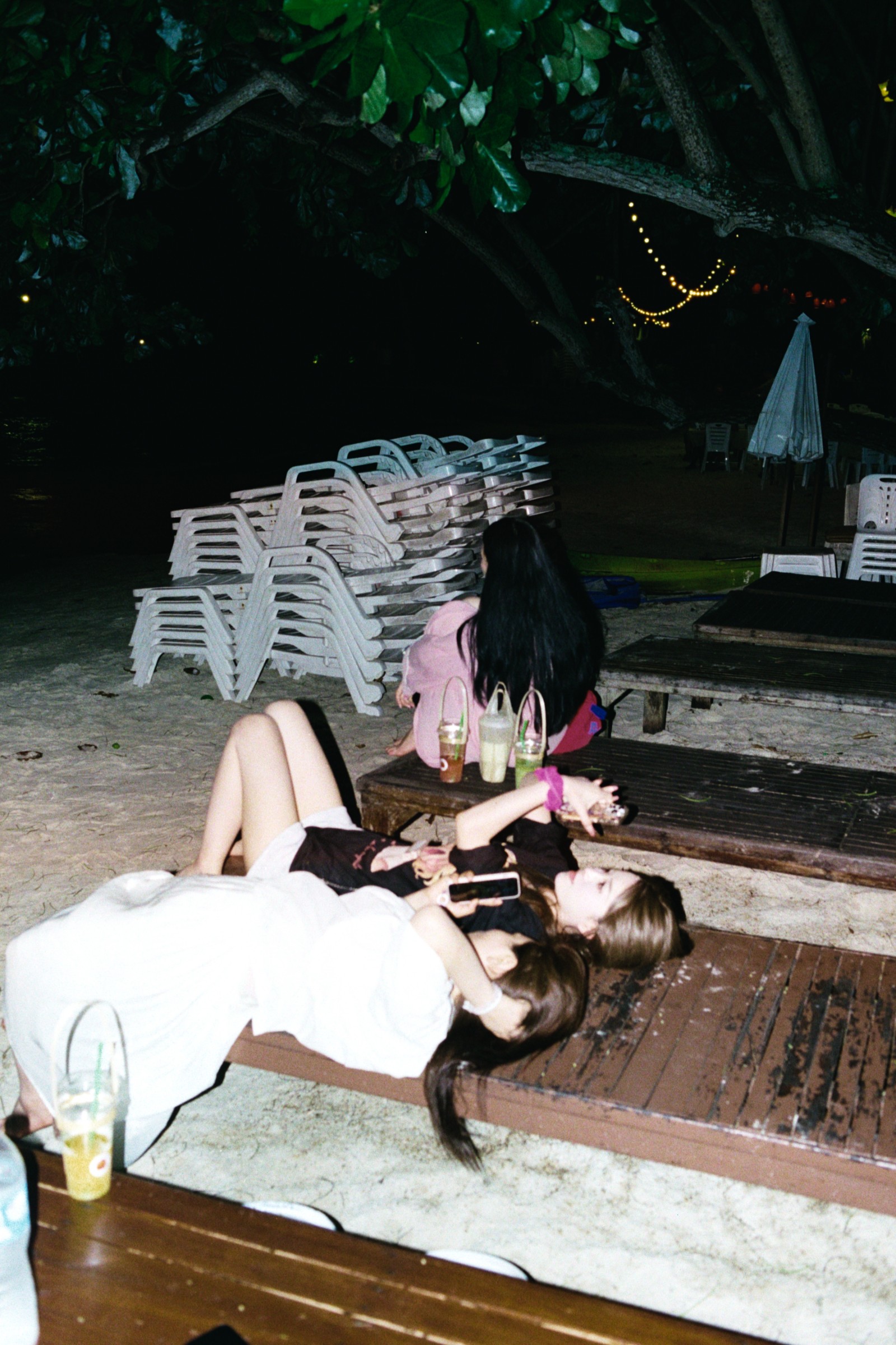 Two women reclining on wooden benches at night
