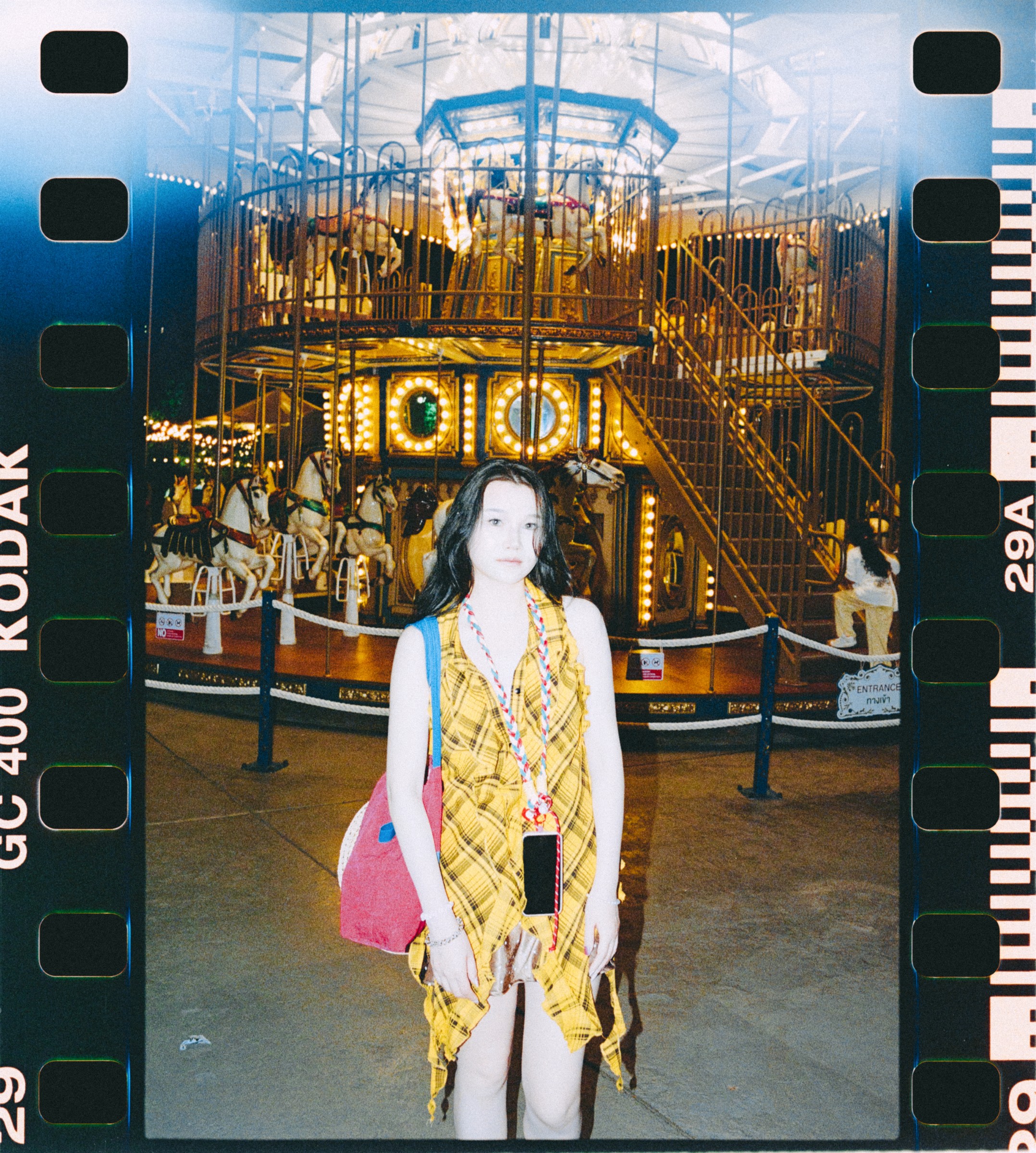 Film-framed portrait of a woman standing before an ornate carousel