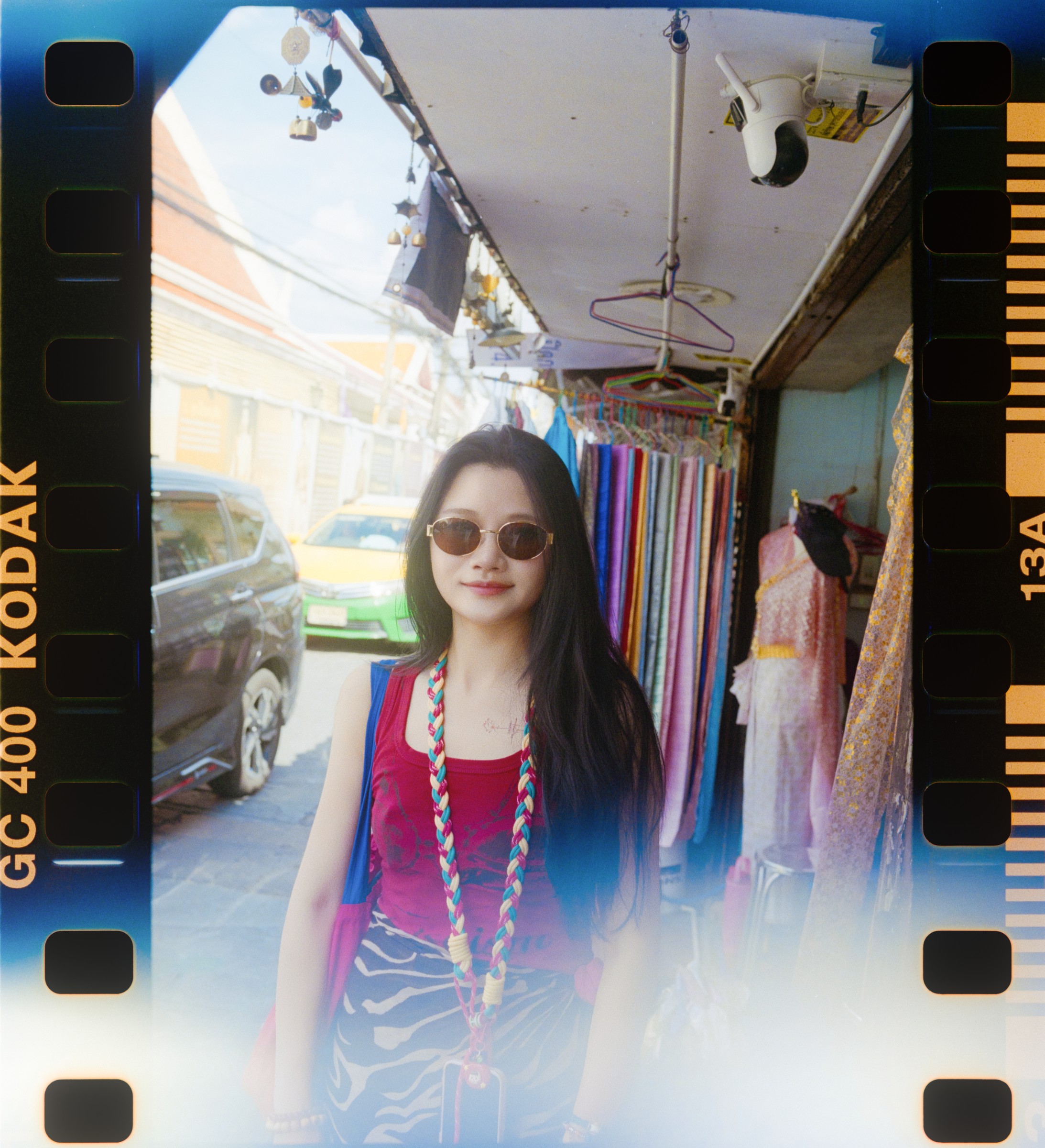 Film-framed portrait of a woman in sunglasses at a market